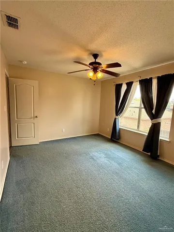 an empty room with windows and fan