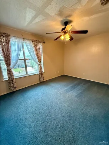 an empty room with windows and fan