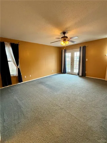 a view of a big room with windows and chandelier fan