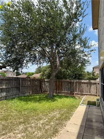 a view of a backyard with large tree and wooden fence