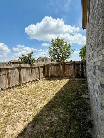 a view of a backyard with large tree and wooden fence