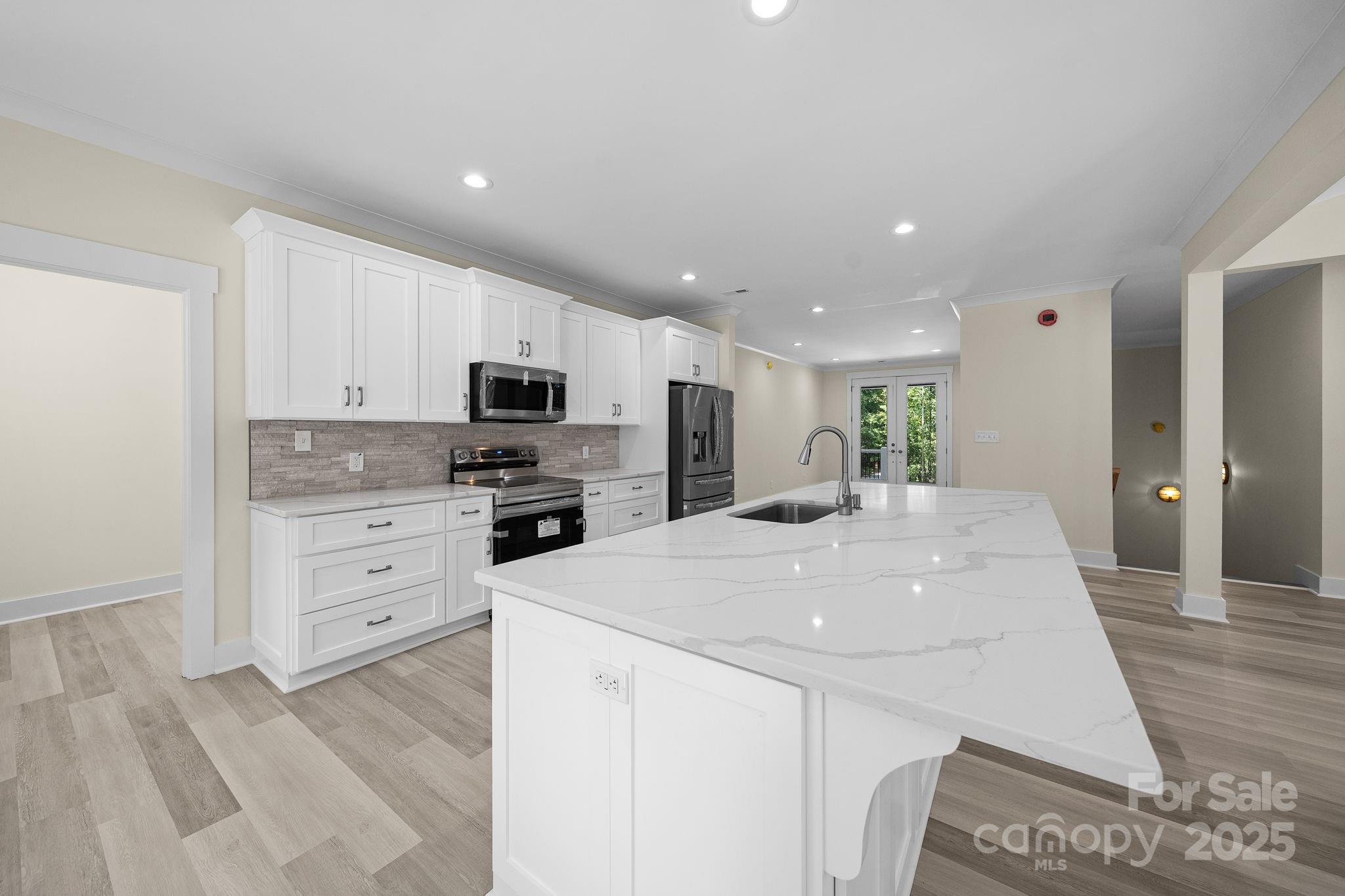 4460 R R L Lane Midland, NC 28107 - Photo 16 of 48 a large kitchen with kitchen island a stove a sink a refrigerator and white cabinets with wooden floor