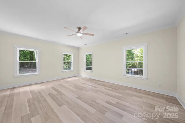 a view of an empty room with a window and wooden floor