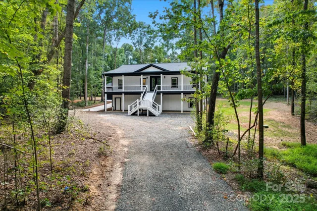 a view of a house with large trees and sitting area