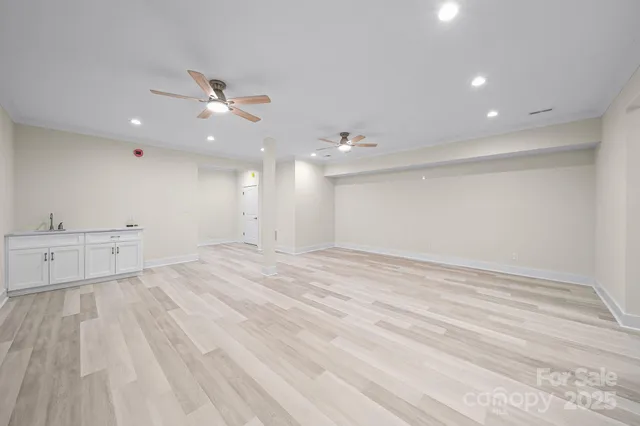 an empty room with wooden floor fan and window