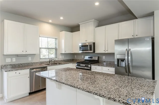 a large kitchen with granite countertop a sink and white cabinets