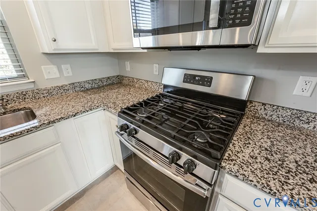 a kitchen with granite countertop a sink stainless steel appliances and white cabinets