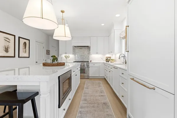 a kitchen with granite countertop white cabinets a sink dishwasher and a stove with wooden floor