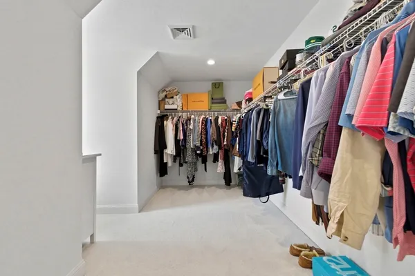 a walk in closet with clothes and shoes