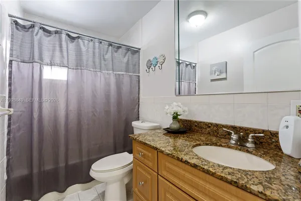 a bathroom with a granite countertop sink toilet and a mirror