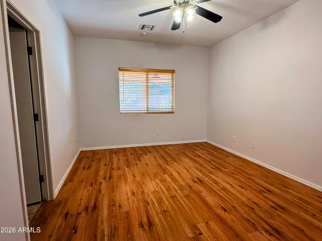 an empty room with wooden floor chandelier and windows