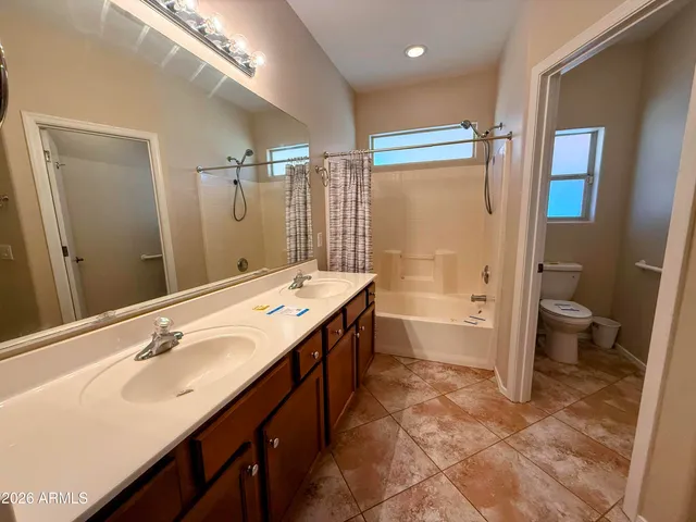 a spacious bathroom with a double vanity sink toilet mirror and bathtub