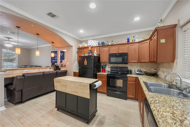 a kitchen with stainless steel appliances granite countertop a stove top oven a sink dishwasher and a refrigerator with wooden floor