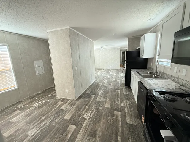 a kitchen with a sink appliances wooden floor and a window