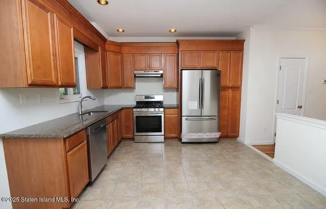 a large kitchen with stainless steel appliances granite countertop a stove a refrigerator and a sink