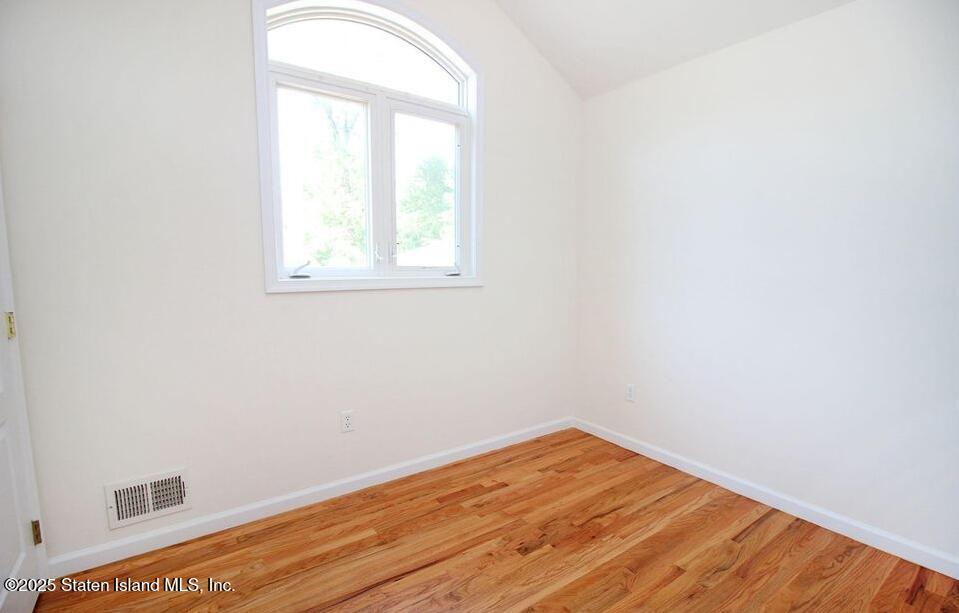 65 Gwenn Loop Staten Island, NY 10314 - Photo 9 of 18 an empty room with wooden floor and windows