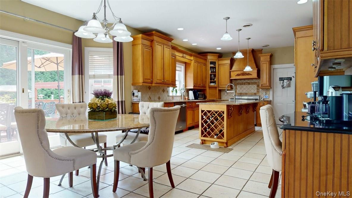 9 Roselawn Road Highland Mills, NY 10930 - Photo 12 of 46 Gorgeous high-end Kitchen featuring Bosch double wall ovens, enormous island with sink, built-in style refrigerator, Stainless steel Viking gas range, st. steel dishwasher, built-in trash bin, custom pantry cabinet, desk,granite table for 5-6 people that matches island and counters.st. steel dishwasher, ceramic backsplash, glass-front cabinets, light tile patterned ceramic floors, and designer lighting over island and table, plus recessed lighting