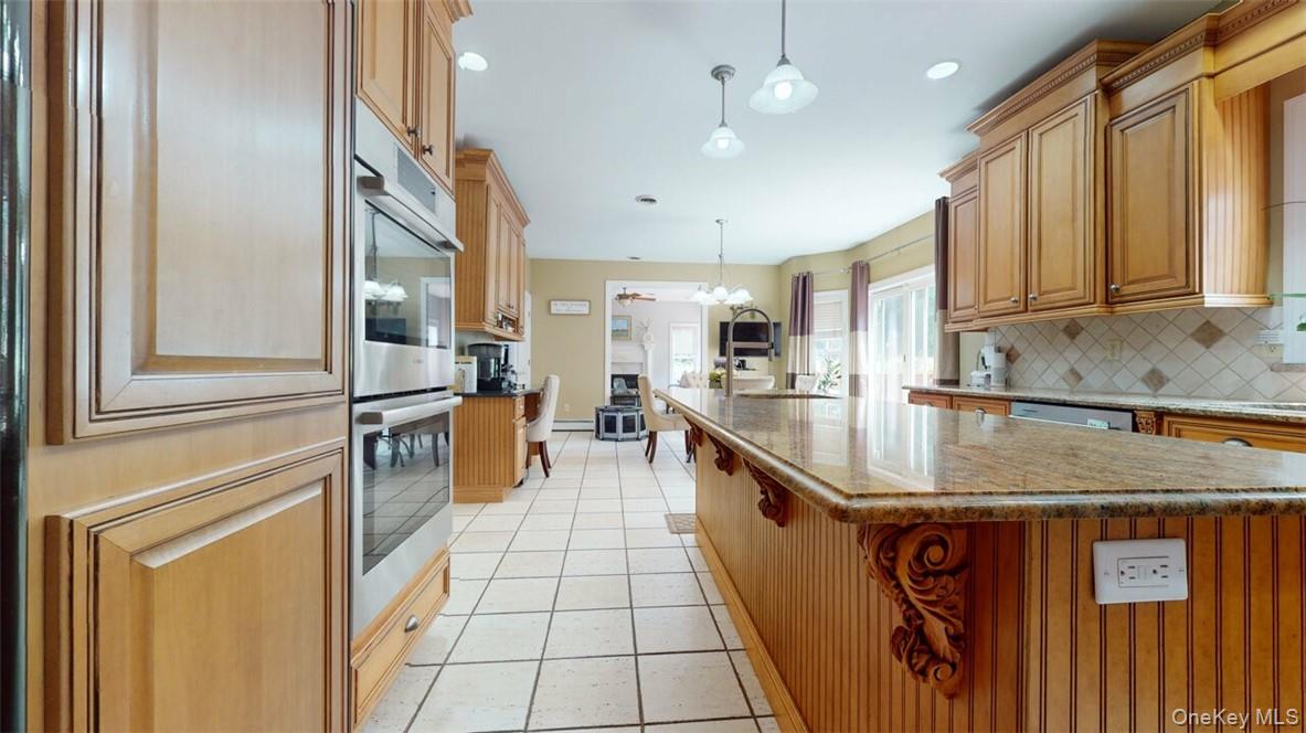 9 Roselawn Road Highland Mills, NY 10930 - Photo 18 of 46 Kitchen featuring a kitchen island with sink, backsplash, hanging light fixtures, and stainless steel appliances