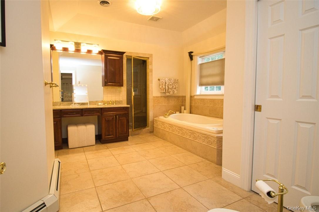 9 Roselawn Road Highland Mills, NY 10930 - Photo 25 of 46 Tray ceiling in extremely spacious Primary Bathroom with marble floors, dual-vanities ,large Carreras marble tiled walk-in shower, Jacuzzi tub, new granite counter, new sinks, new faucets, new top-of-the-line light fixtures, new towel rods, big walk-in storage closet with tons of shelving
