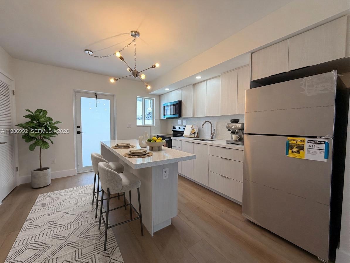 1904 Southwest 17th Avenue, Unit 3 Miami, FL 33145 - Photo 6 of 15 a kitchen with a refrigerator a stove a sink and a dining table