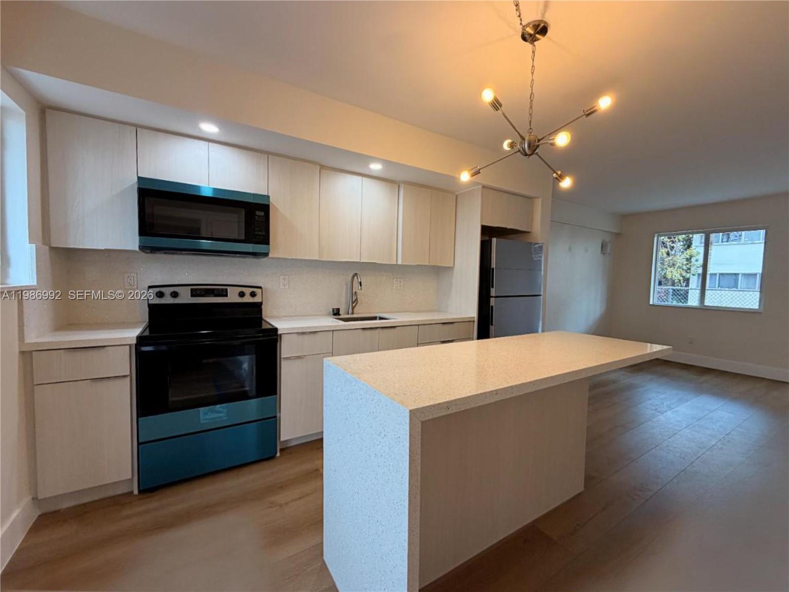 1904 Southwest 17th Avenue, Unit 3 Miami, FL 33145 - Photo 9 of 15 a kitchen with kitchen island white cabinets and stainless steel appliances