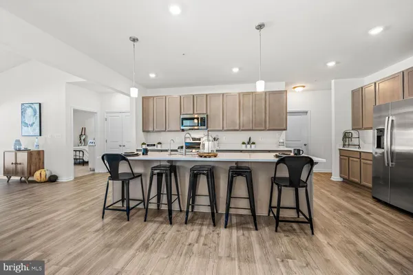 a kitchen with stainless steel appliances granite countertop a dining table chairs refrigerator sink and cabinets