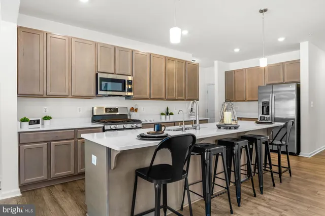 a kitchen with stainless steel appliances granite countertop a stove a sink a microwave a refrigerator and white cabinets