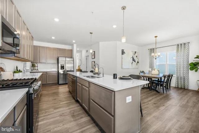 a kitchen with stainless steel appliances a stove a sink a kitchen island with chairs and wooden floor