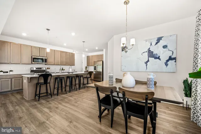 a kitchen with kitchen island a dining table chairs stainless steel appliances and cabinets