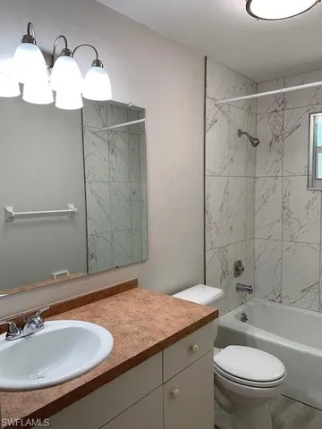 a bathroom with a granite countertop sink mirror toilet and bathtub