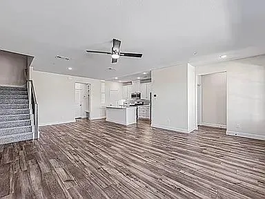 a view of empty room with wooden floor and ceiling fan