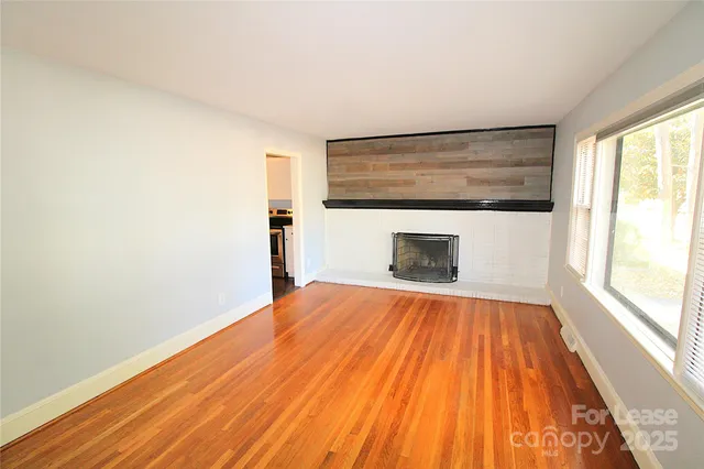 a view of empty room with wooden floor and fireplace