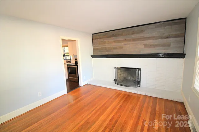 a view of empty room with wooden floor and fireplace