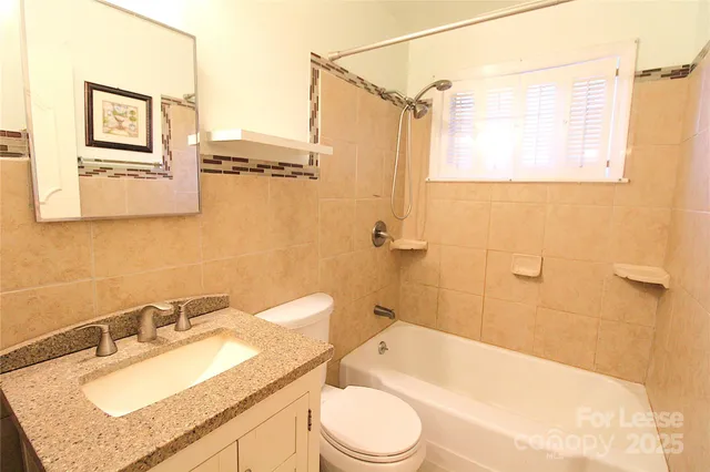 a bathroom with a granite countertop sink toilet a mirror and shower