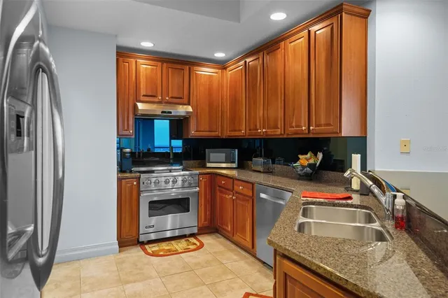 a kitchen with stainless steel appliances granite countertop a stove a sink and a refrigerator