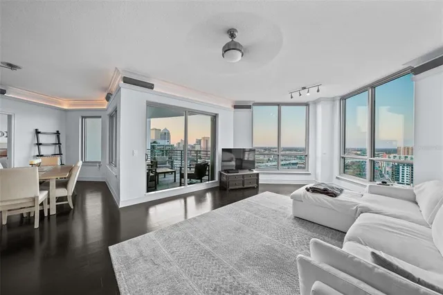 a living room with furniture large windows and wooden floor