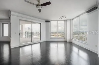 a view of an empty room with wooden floor and a window