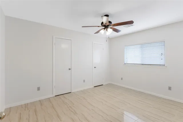 an empty room with a window and a fan