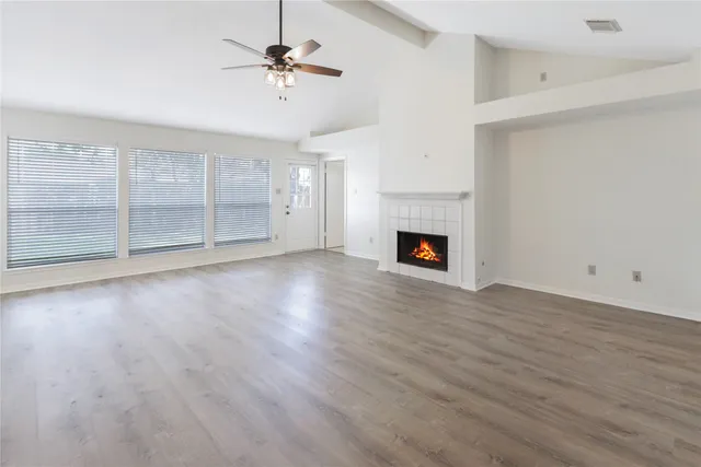 an empty room with wooden floor a fireplace and windows