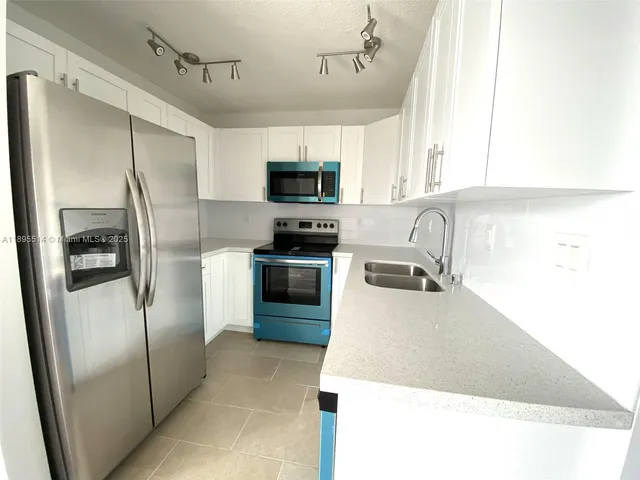 a kitchen with stainless steel appliances granite countertop a refrigerator a stove a sink a microwave and cabinets