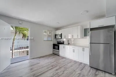 a kitchen with a refrigerator a stove top oven and wooden floor