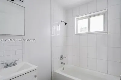 a white bath tub sitting next to a white sink and vanity