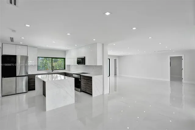 a view of a kitchen with kitchen island a sink wooden floor and a refrigerator