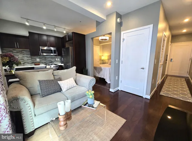 a living room with stainless steel appliances furniture and a wooden floor
