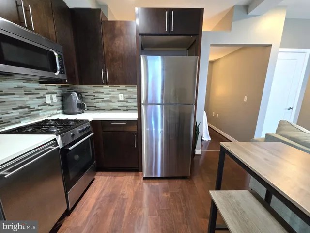 a kitchen with stainless steel appliances and wooden floor