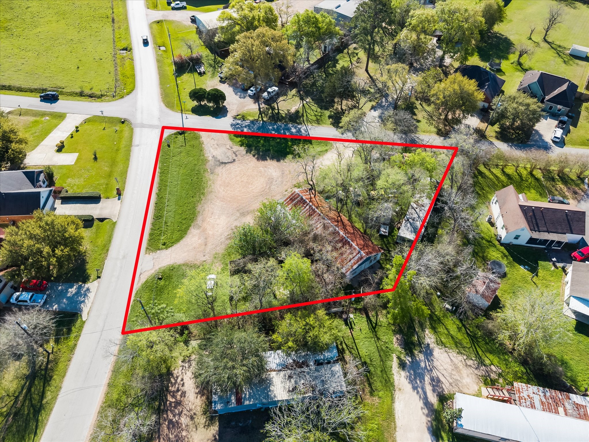Spacious corner lot outlined in red featuring a mix of open and wooded areas.  Ideal for development, lots of possibilities.