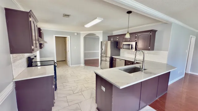 a kitchen with stainless steel appliances kitchen island granite countertop a sink and refrigerator