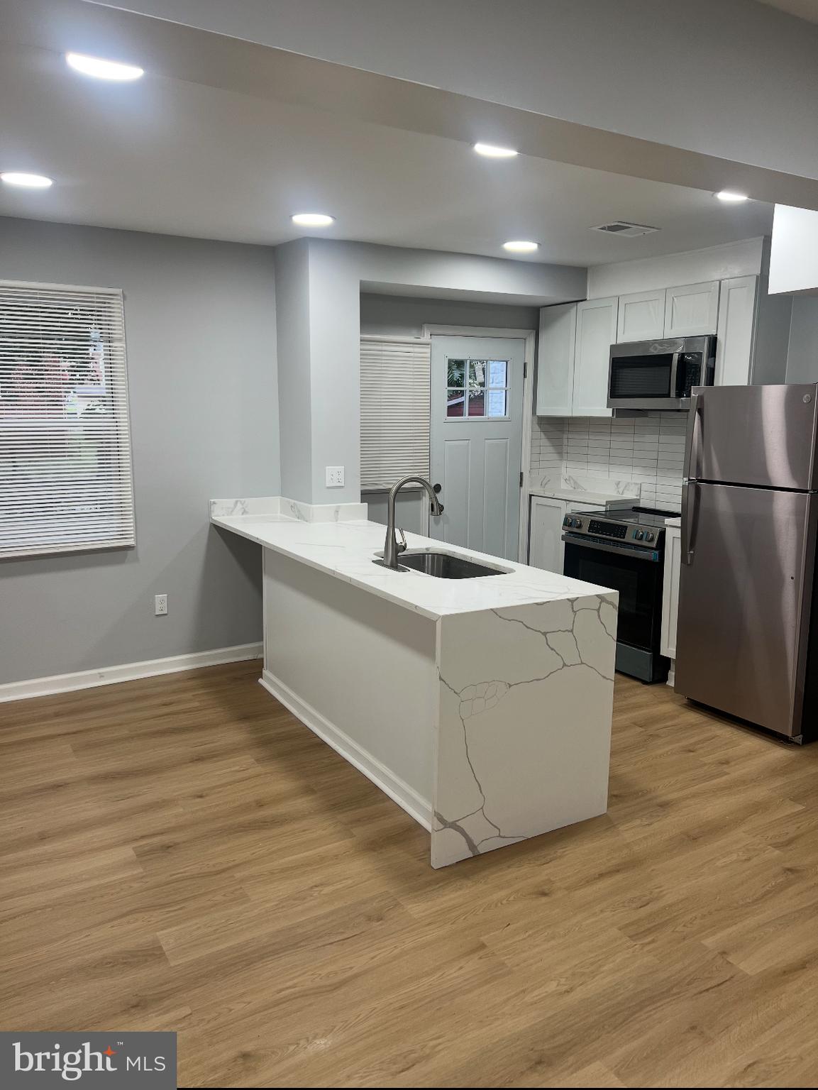 1208 Congress Street Southeast Washington, DC 20032 - Photo 5 of 12 a living room with stainless steel appliances kitchen island granite countertop a stove a sink a refrigerator and white cabinets with wooden floor