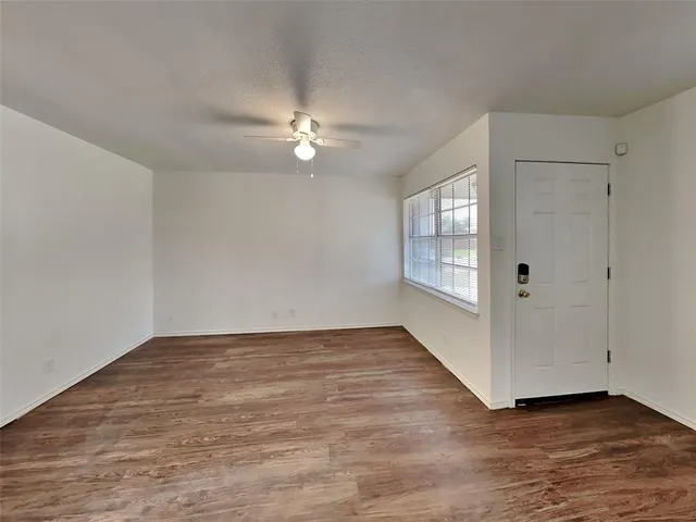 a view of an empty room with a window and wooden floor