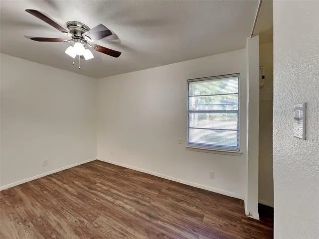 a view of a room with wooden floor and a ceiling fan